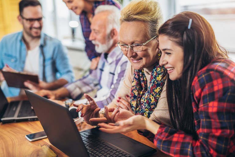 Junge Freiwillige helfen älteren Menschen am Computer.