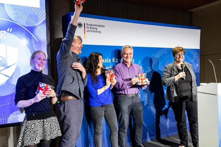 Preisverleihung durch Dr. Heike Prasse, Leiterin des Referats „Vernetzung und Sicherheit digitaler Systeme“ im BMBF mit allen Beteiligten auf der Bühne.