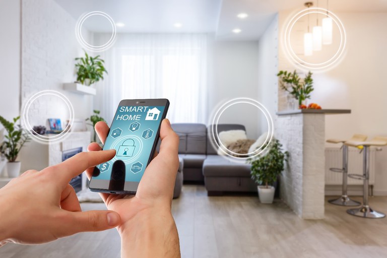 Hand hält Smartphone mit SmartHome App. Im Hintergrund Wohnzimmer.