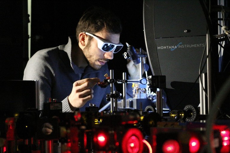 Forscher sitzt vor einem Laboraufbau zur Erforschung von Quantenspeichern auf Basis von Seltenerdionen.