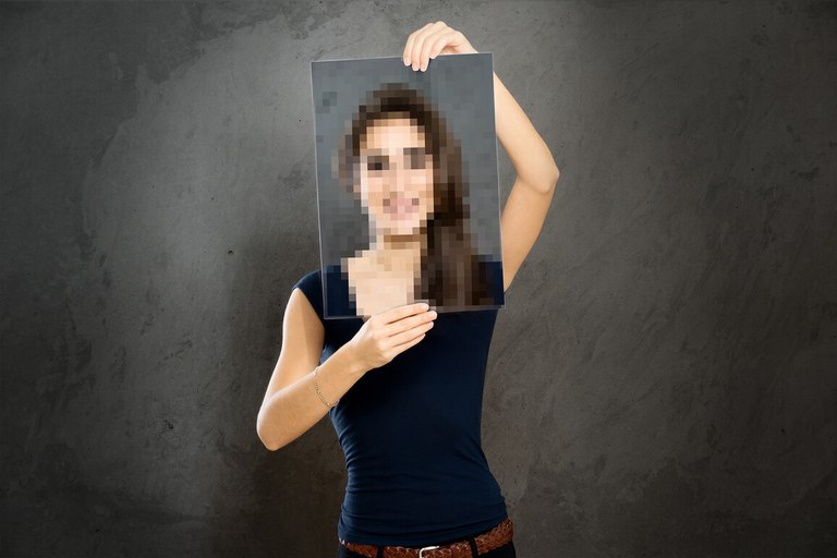 Frau hält ein verpixeltes Portrait von sich vor ihr Gesicht, um ihre Daten zu schützen