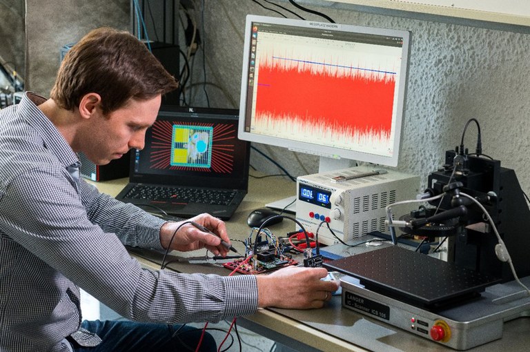Mann arbeitet an einem Versuchsaufbau mit Computer und Messgeräten für die Seitenkanalmessungen eines Prozessorchips 