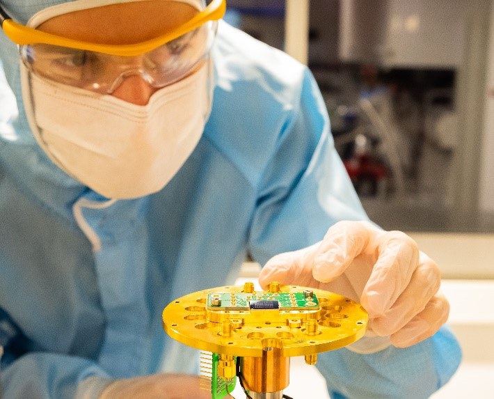 Larborarbeiter hält einen Aufbau zur Erforschung eines Multi-Detektorsystems zur Quantenkommunikation in der Hand
