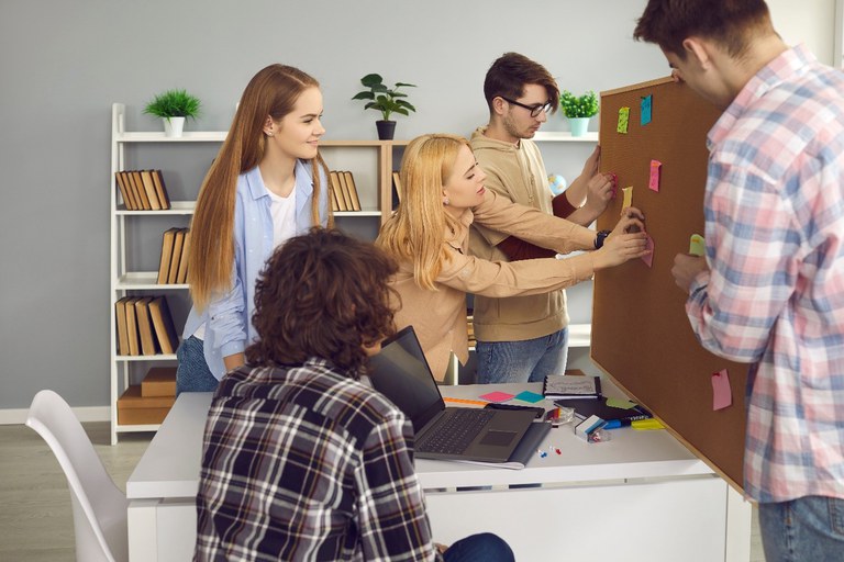 Junge Menschen dikutieren vor einer Pinwand